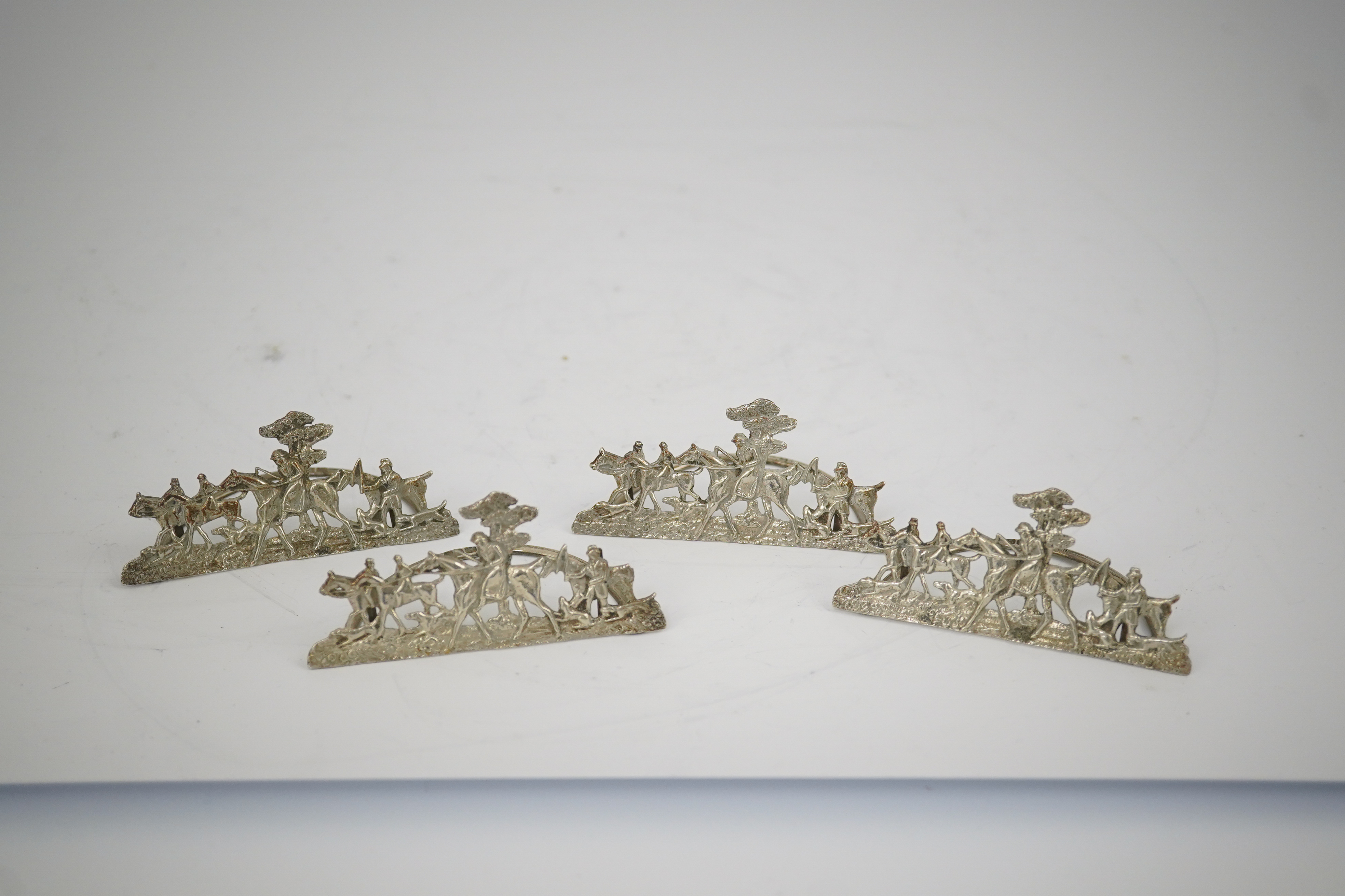 A set of four Edwardian pierced silver 'hunting scene' menu holders, by Stuart Clifford